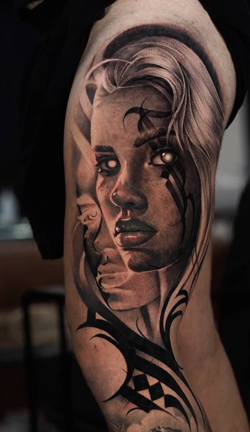 Arm tattoo portrait of a woman with detailed shading, unique eye design and decorative black linework elements